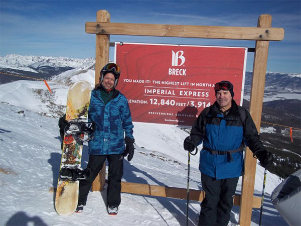 Friends on top of a mountain to snowboard
