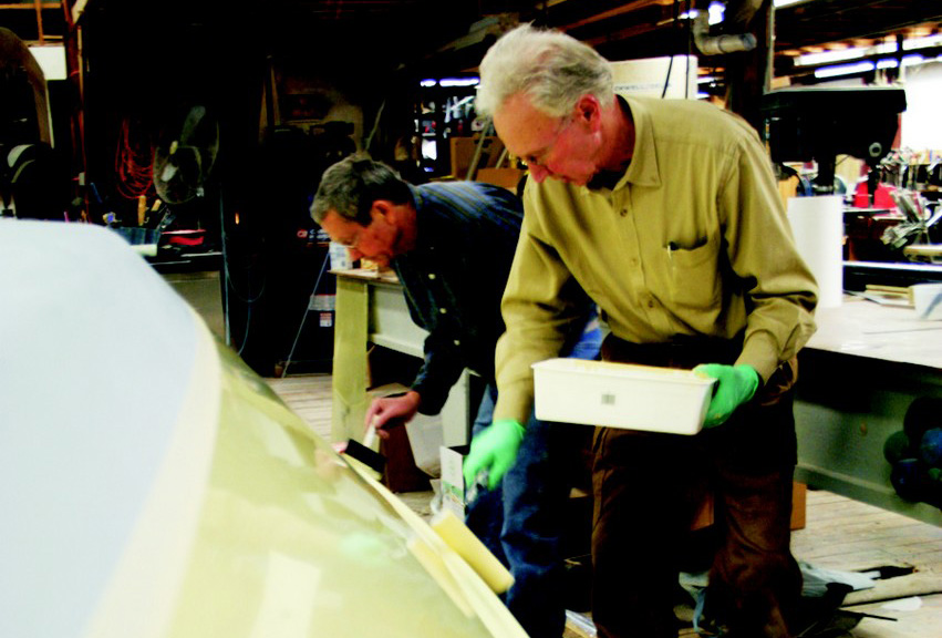 Meade Gougeon rolls a coat of paint on the overturned hull while his brother Jan follows up with with a tipping brush